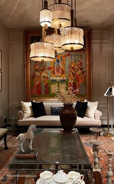 a living room filled with furniture and a chandelier hanging from the ceiling over a coffee table