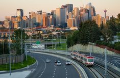 a train traveling down the tracks in front of a large cityscape with tall buildings