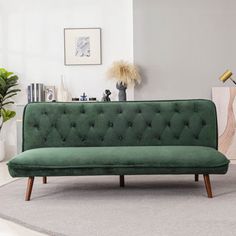 a green couch sitting on top of a carpeted floor next to a potted plant