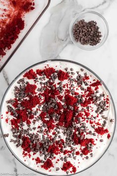 red velvet cake with white frosting and sprinkles in a glass dish