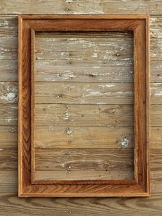 an old wooden frame hanging on the side of a wood paneled wall with peeling paint