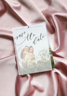 save the date book laying on pink satin