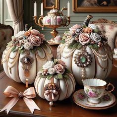 three white pumpkins decorated with flowers and pearls, sitting on a table in front of a mirror