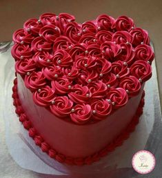 a heart - shaped cake with red icing and pearls on top is shown in the shape of a flower