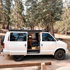 a white van parked in the woods with its door open and it's driver inside