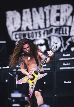 a man with long hair playing an electric guitar