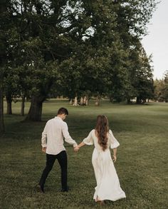 a man and woman holding hands in the grass