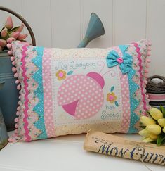 a decorative pillow sitting on top of a table next to a vase with flowers in it