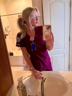 a woman taking a selfie in front of a bathroom mirror with her cell phone