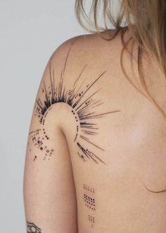 the back of a woman's shoulder with an abstract tattoo design on her left shoulder