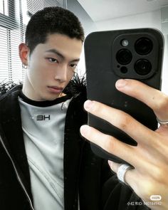 a young man taking a selfie with his cell phone in front of the camera