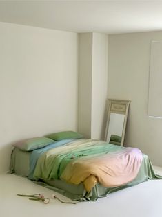 a bed sitting in the middle of a room next to a mirror and flower on the floor