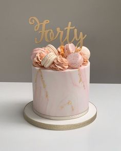 a pink and gold cake with the word forty on top