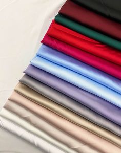 a stack of different colored sheets sitting on top of each other in front of a white sheet