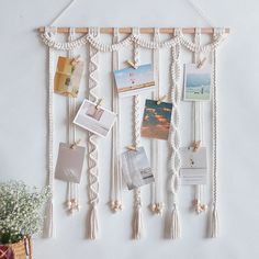 a white wall hanging with pictures, photos and other things attached to the strings on it