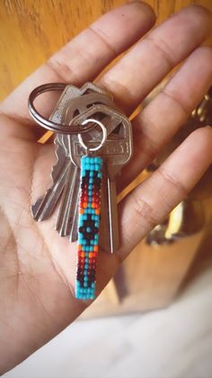 a person is holding a key chain with beads on it