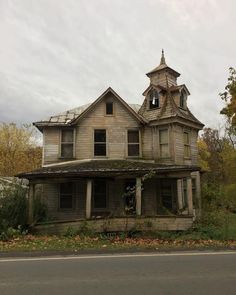 an old run down house sitting on the side of a road