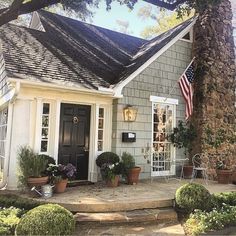 a house with potted plants and an american flag on the front door