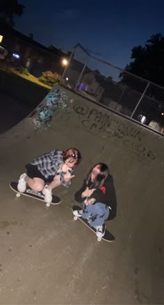 two people sitting on skateboards at the top of a ramp