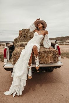 a woman sitting on the back of a pick up truck with hay bales behind her