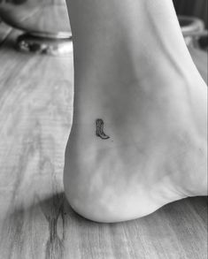 a small boot tattoo on the foot of a woman's foot, with a tiny boot