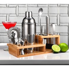 a set of cocktail shakers and glasses on a tray with limes next to it