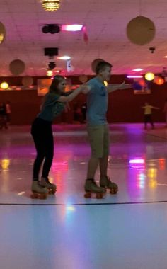 two people riding skateboards on a brightly lit floor