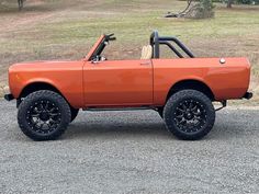 an orange car parked on top of a gravel road