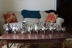 a group of silver cups sitting on top of a wooden table next to a couch