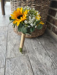 a bouquet of sunflowers and baby's breath sits on the floor next to a basket