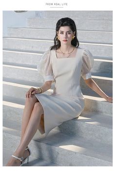 a woman is sitting on the steps wearing a dress and heels with her legs crossed