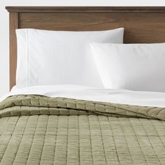 an unmade bed with white pillows and green bedspread in a hotel room