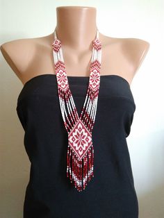 a woman wearing a black top with red and white beaded necklace on her neck