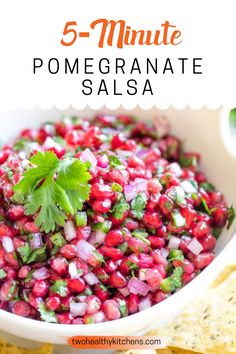 a white bowl filled with pomegranate salsa next to tortilla chips