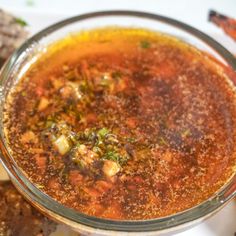 a glass bowl filled with soup next to crackers