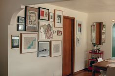 a dining room table with chairs and pictures on the wall next to it's doorway