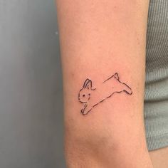 a small cat tattoo on the right inner arm and shoulder, it looks like an outline