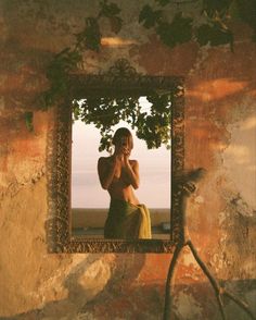 a woman is taking a selfie in a mirror with vines on the wall behind her