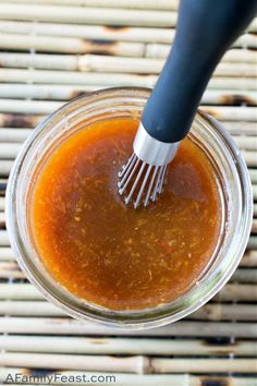 a glass jar filled with sauce and a whisk sticking out of the top