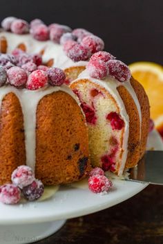 a bundt cake with white frosting and berries on top is sitting on a plate