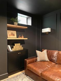 a brown leather couch sitting in a living room next to a wall mounted book shelf