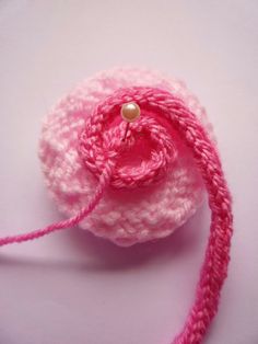 a pink crocheted object with a button on it