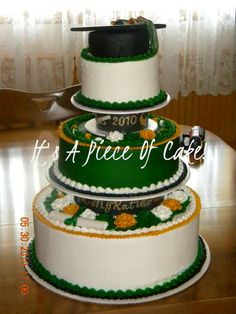 three tiered cake decorated with green and white frosting, topped with a graduation cap