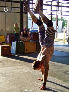 a man is doing a handstand in the middle of an indoor gym area