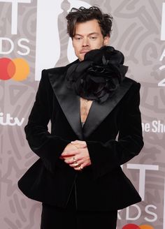 a man in a black suit with a flower on his head