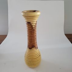 a small wooden vase sitting on top of a table next to a white wall and floor