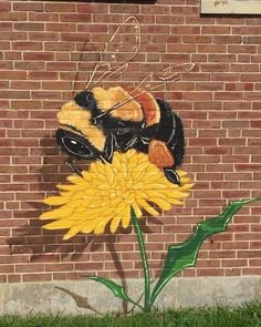 a painting of a bee sitting on top of a yellow flower next to a brick wall