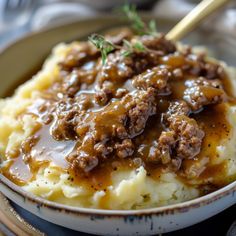 a bowl filled with mashed potatoes covered in gravy and topped with meat