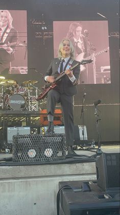 a man in a suit and tie playing an electric guitar on stage with other instruments