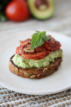 an avocado and tomato sandwich on a white plate